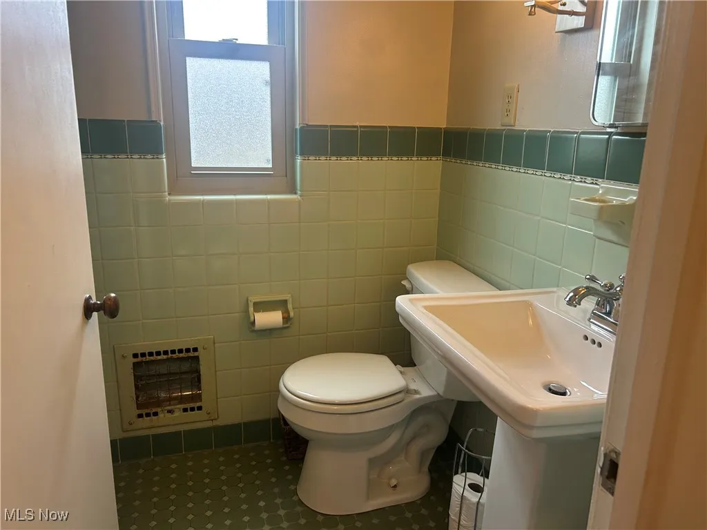 Bathroom with heating unit, tile walls, and wainscoting