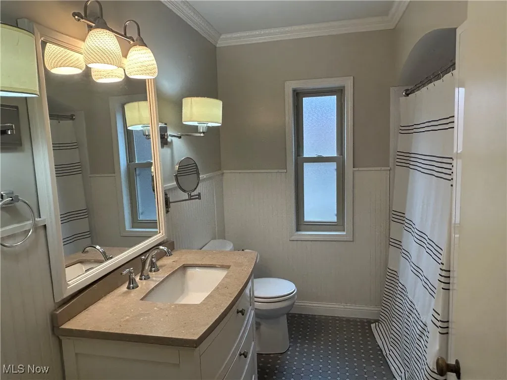 Bathroom with a wainscoted wall, vanity, a shower with shower curtain, and ornamental molding