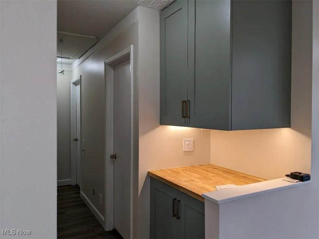 Hallway with attic access, dark wood-type flooring, and a textured ceiling