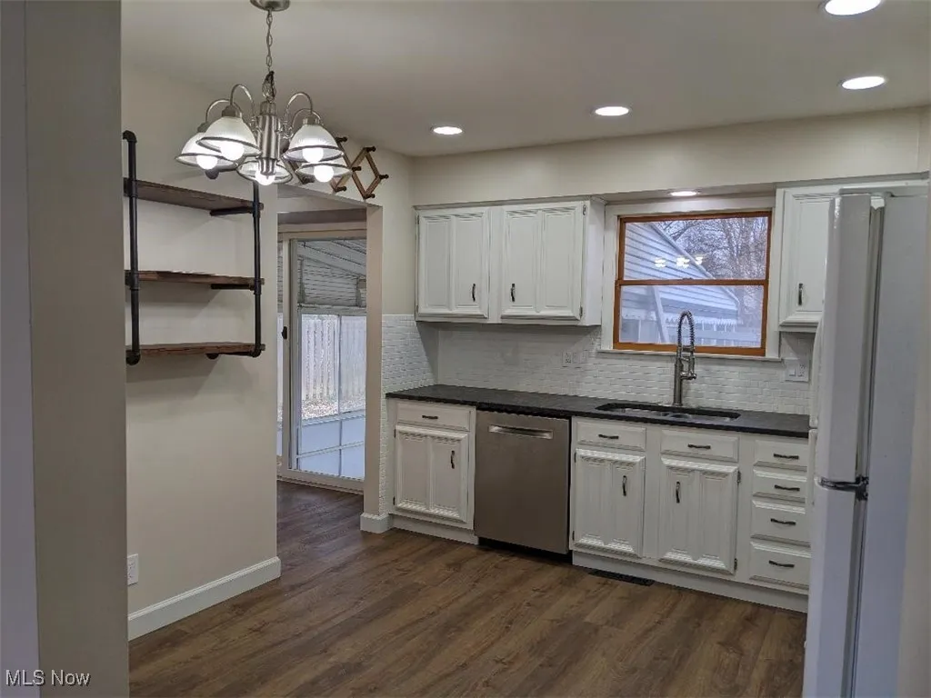 Kitchen featuring freestanding refrigerator, plenty of natural light, dishwasher, white cabinets, and recessed lighting