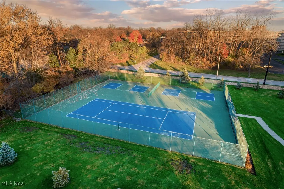 View of tennis court featuring a view of trees