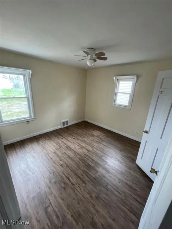 Spare room featuring dark wood-style floors and ceiling fan