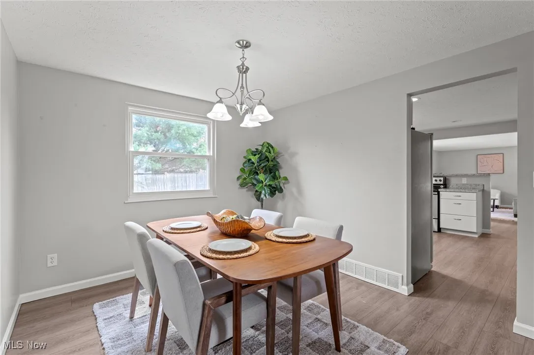 Dining room with a textured ceiling, light wood-type flooring, and a chandelier