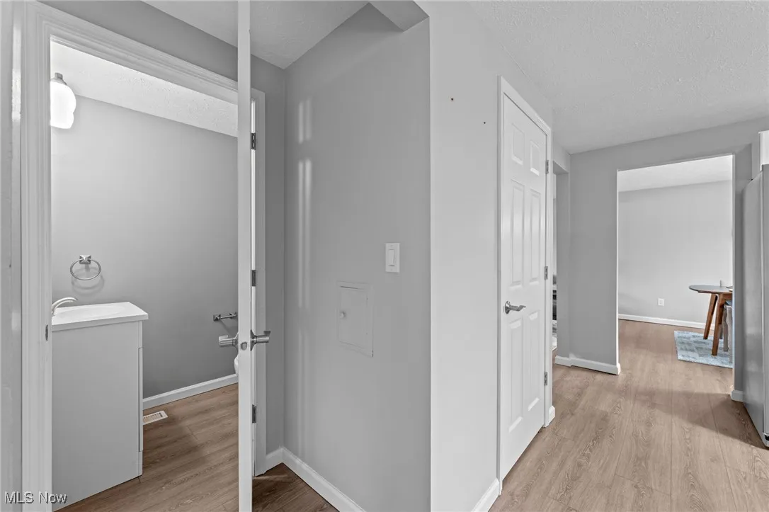 Hallway featuring light wood-style flooring and a textured ceiling