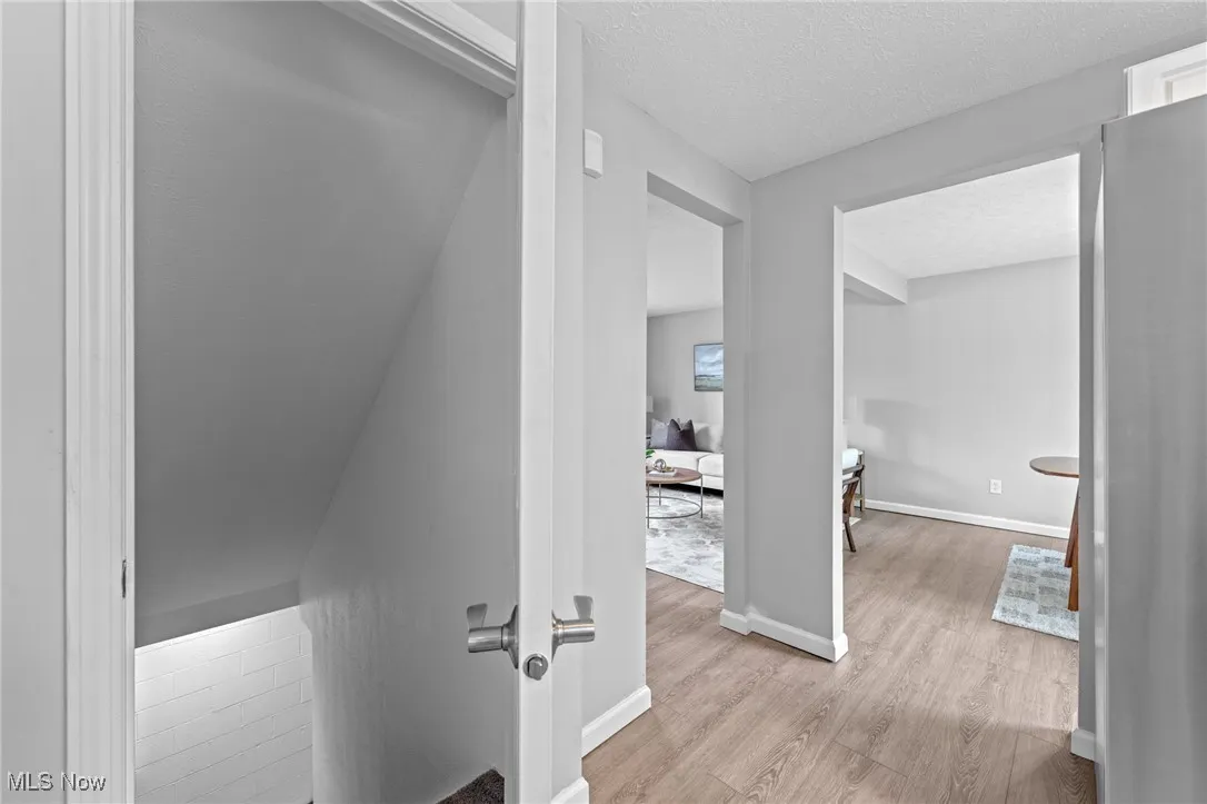 Corridor featuring a textured ceiling and light wood finished floors