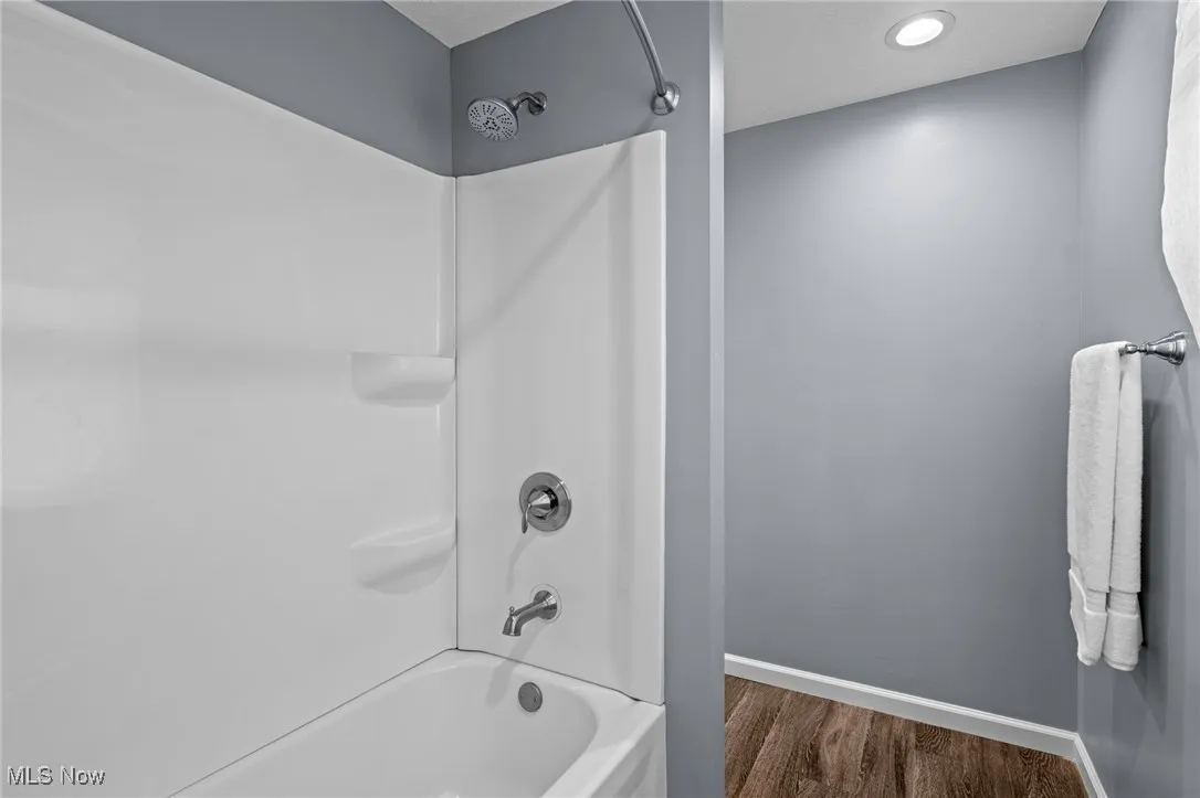 Full bath with shower / tub combination and dark wood-style flooring