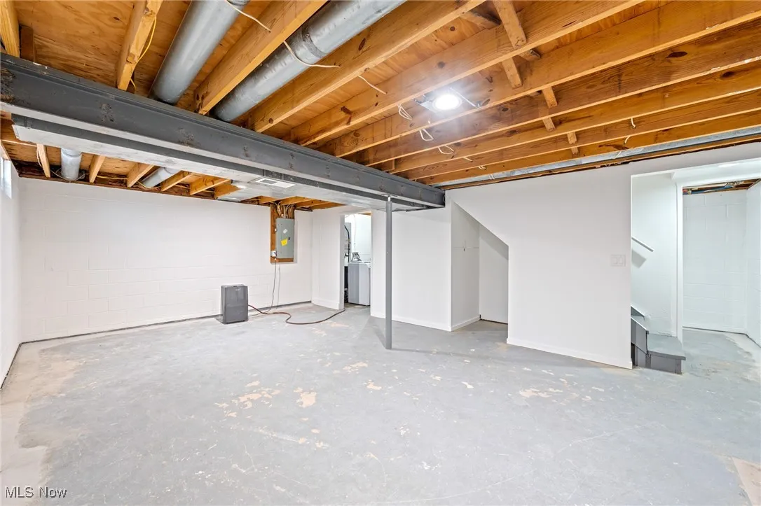 Unfinished below grade area with stairway and electric panel