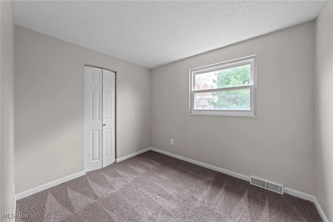 Carpeted empty room with baseboards and a textured ceiling
