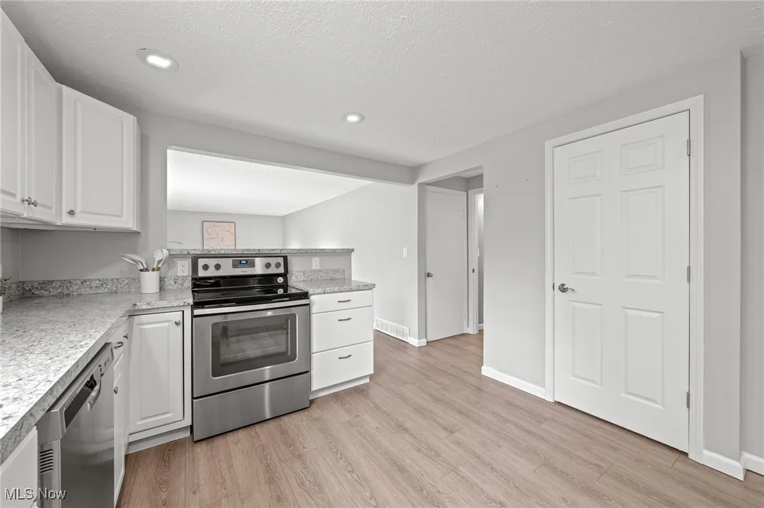 Kitchen featuring stainless steel appliances, white cabinetry, light countertops, a textured ceiling, and recessed lighting