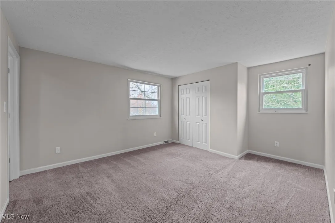 Unfurnished bedroom featuring a textured ceiling, a closet, and light colored carpet