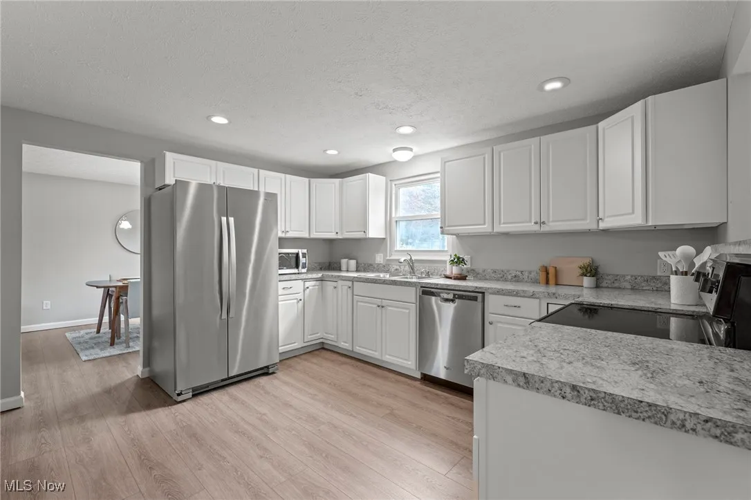 Kitchen with white cabinets, stainless steel appliances, a textured ceiling, light countertops, and recessed lighting