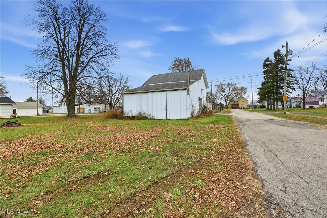 View of side of home with a lawn, asphalt driveway, an outdoor structure, and a residential view