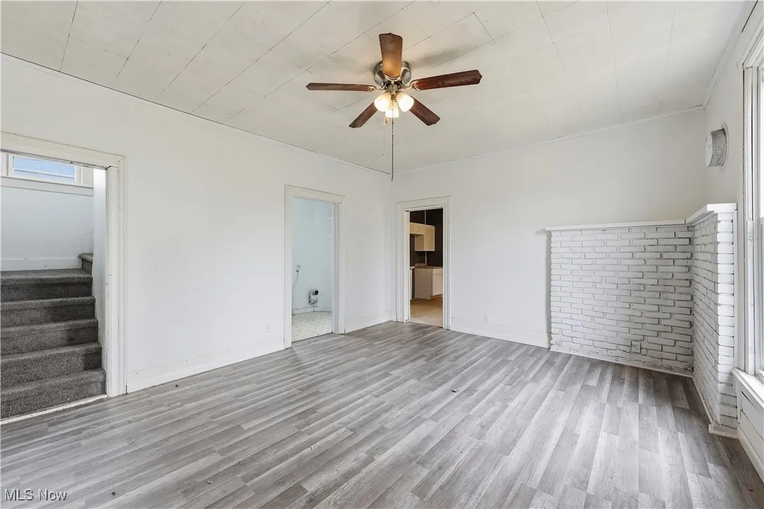 Spare room with stairs, light wood finished floors, and ceiling fan