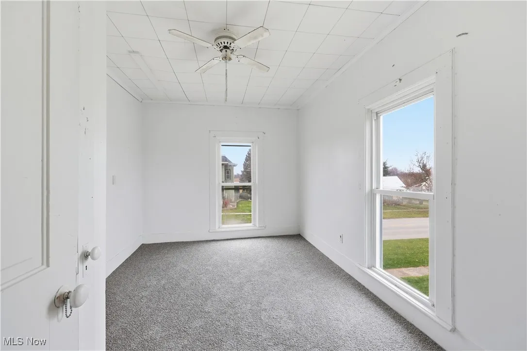Carpeted spare room featuring ceiling fan and baseboards
