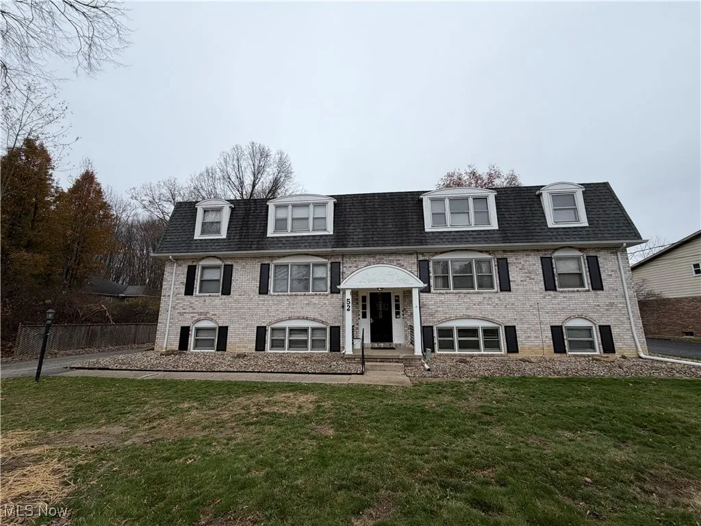 Raised ranch with brick siding, mansard roof, and roof with shingles