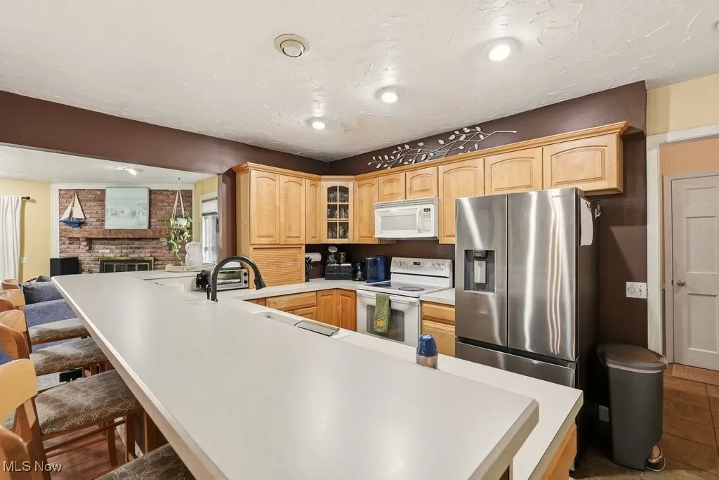 Eat In Kitchen with Breakfast Bar with 4 Chairs, Wood Fireplace, Garbage Disposal, Microwave, Dishwasher, Range, Refrigerator