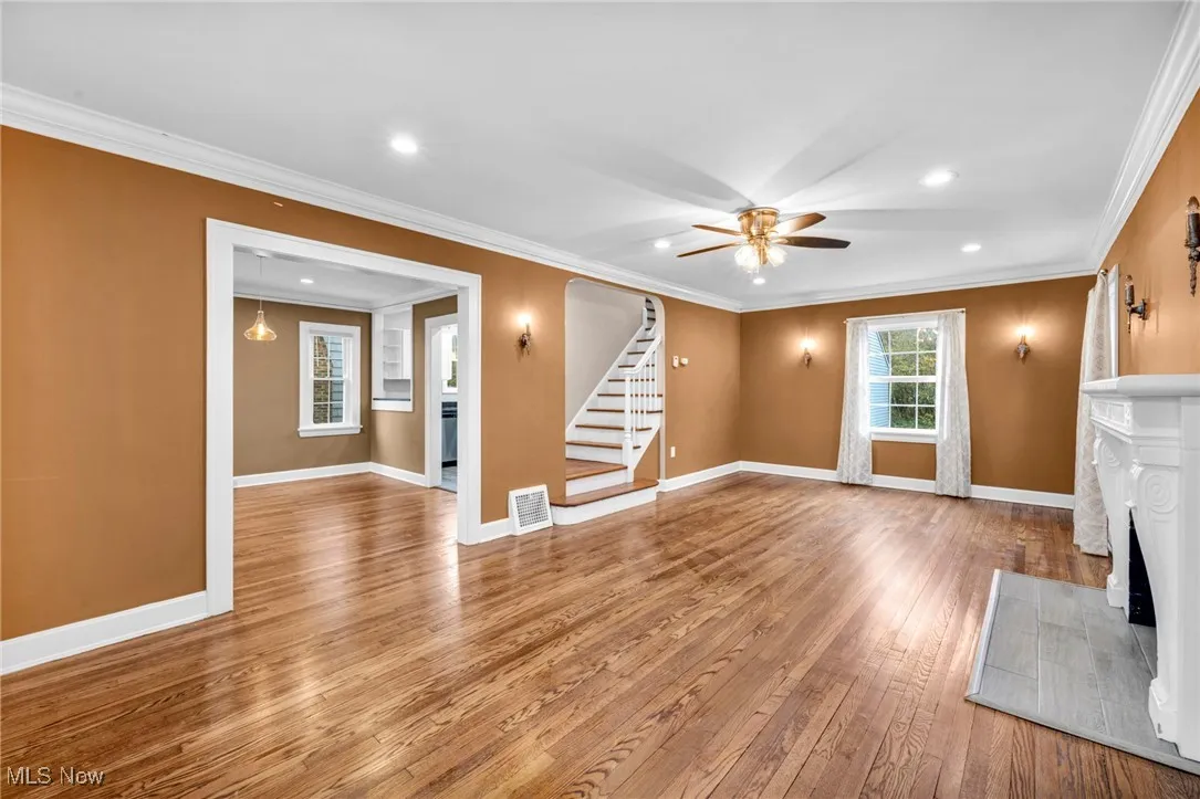 Unfurnished living room with ornamental molding, a fireplace, stairs, hardwood / wood-style floors, and recessed lighting