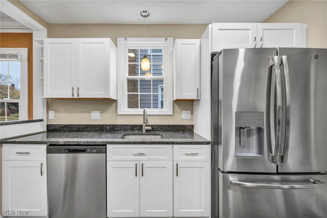 Kitchen featuring appliances with stainless steel finishes, white cabinets, and dark stone counters