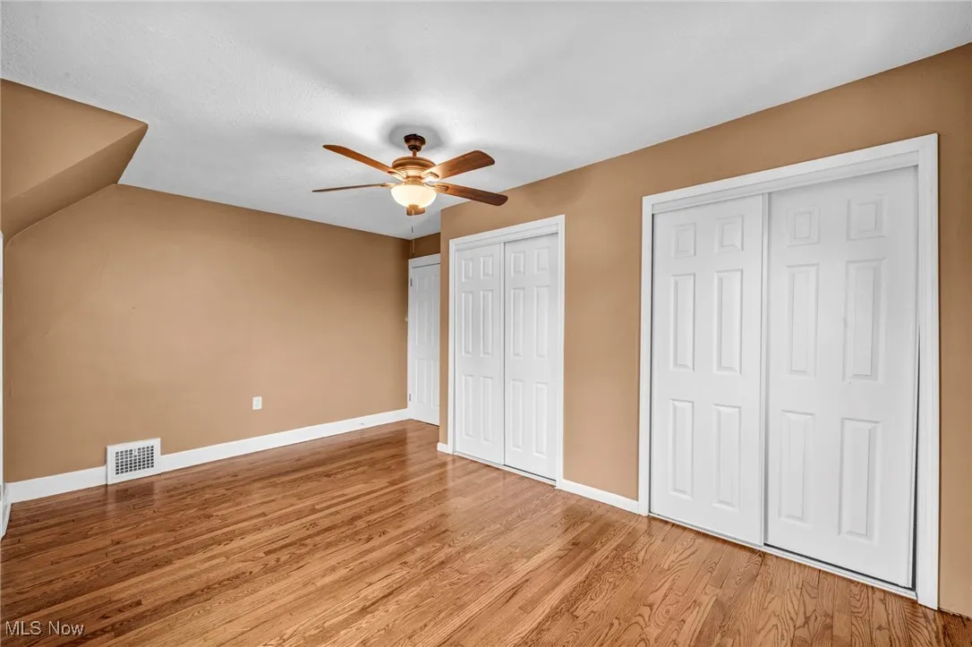 Unfurnished bedroom with multiple closets, a ceiling fan, and light wood-style flooring