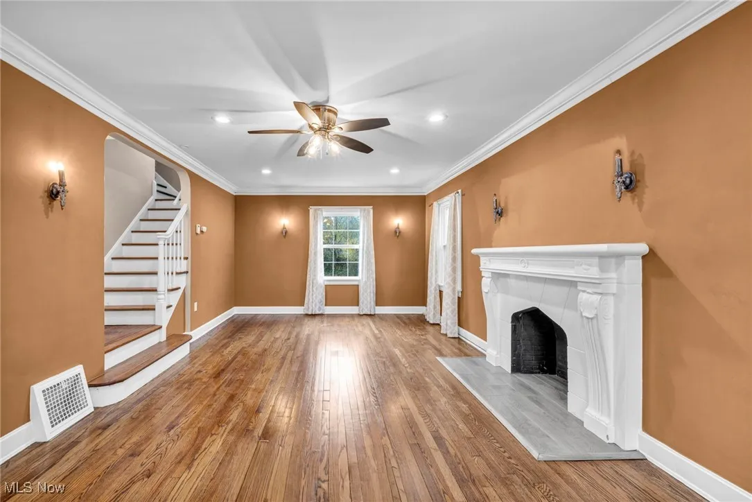 Unfurnished living room featuring ornamental molding, stairway, hardwood / wood-style floors, recessed lighting, and a fireplace