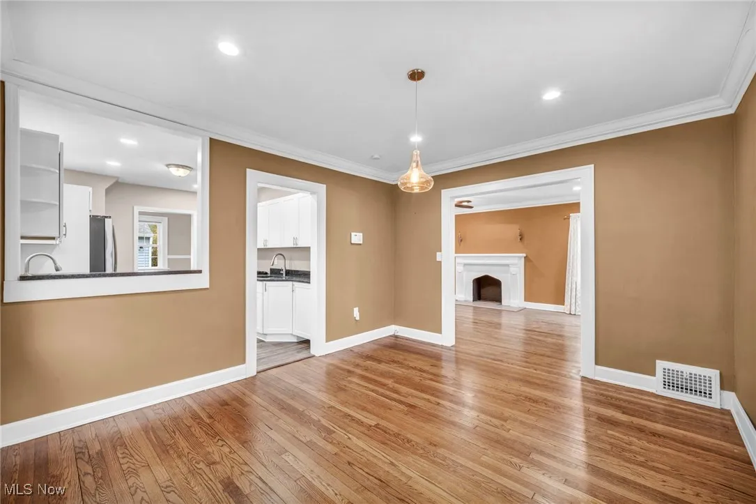 Unfurnished living room featuring light wood-style flooring, recessed lighting, crown molding, and a fireplace with raised hearth