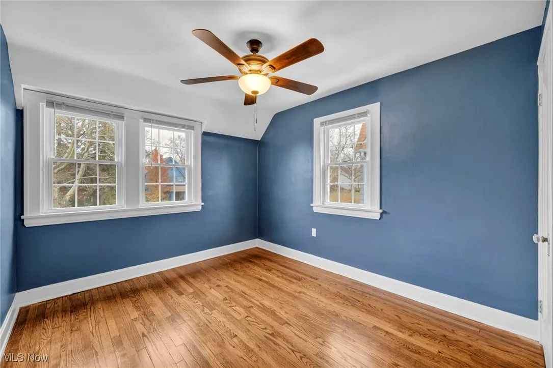 Spare room with hardwood / wood-style flooring, lofted ceiling, and ceiling fan