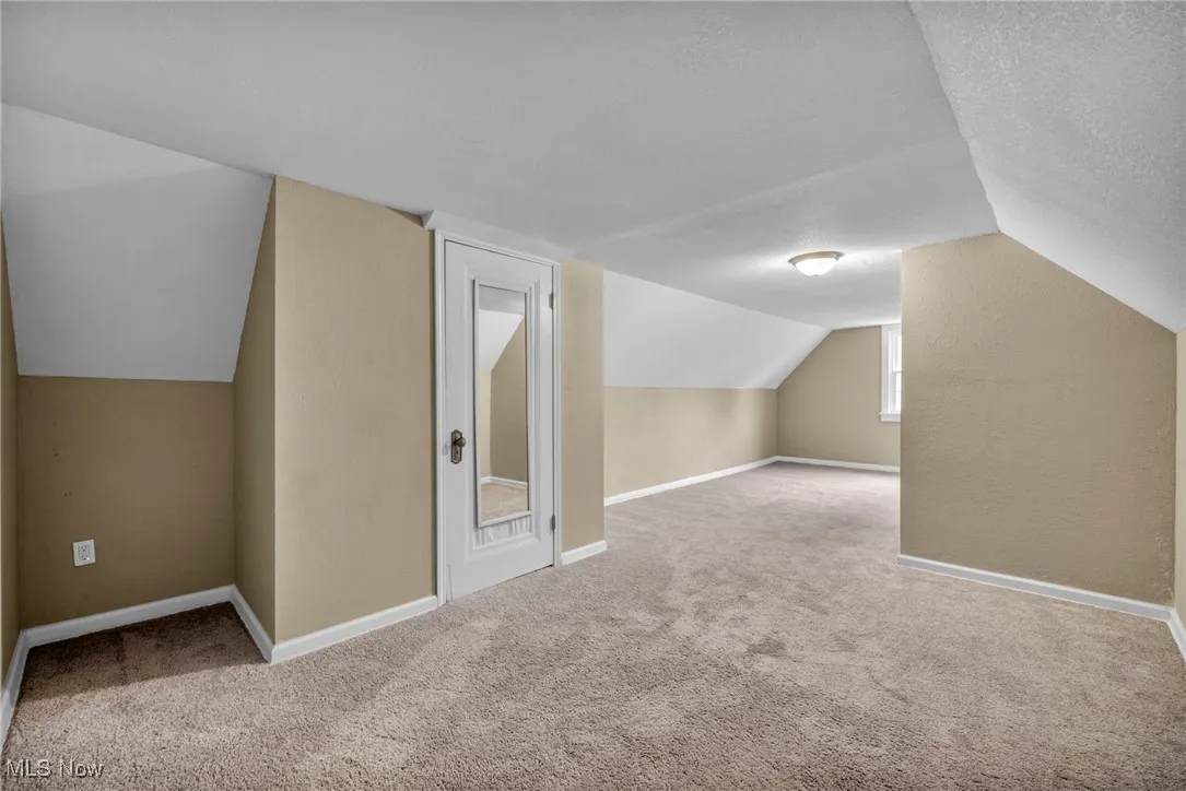 Additional living space featuring carpet floors, lofted ceiling, and a textured ceiling