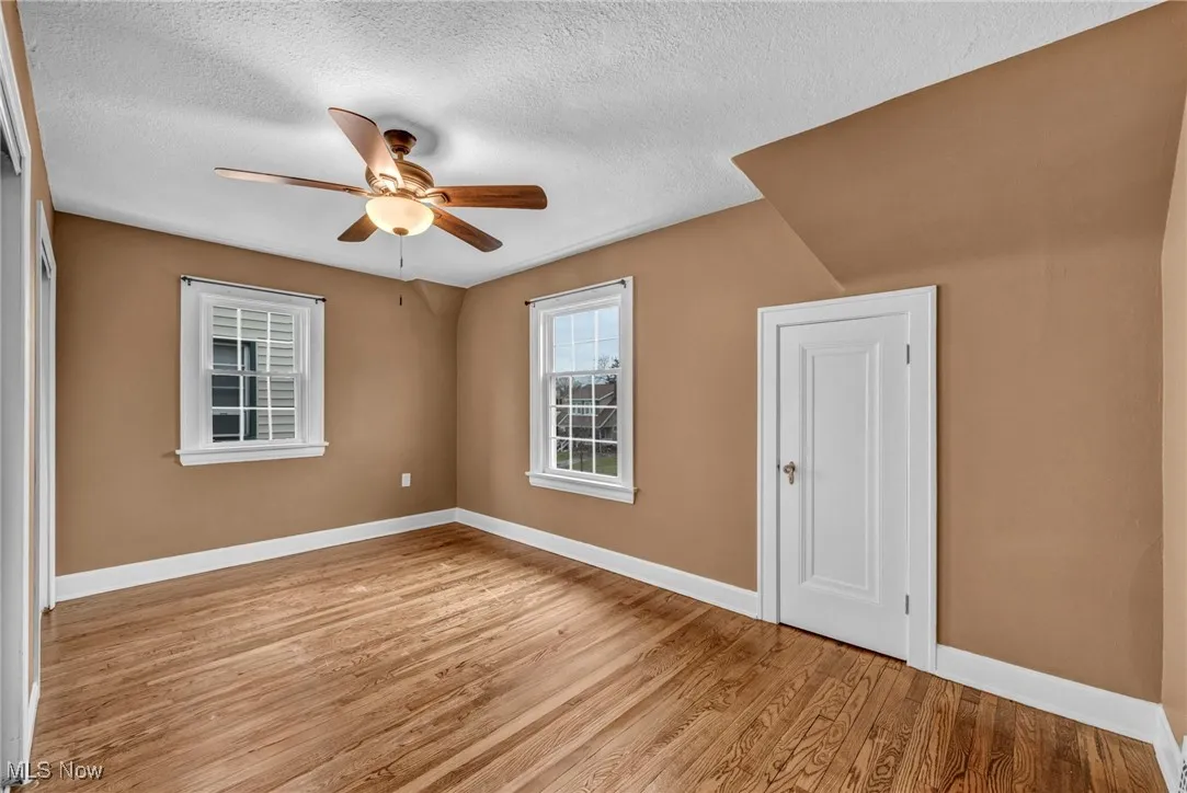 Empty room featuring a textured ceiling, light wood-style floors, and a ceiling fan
