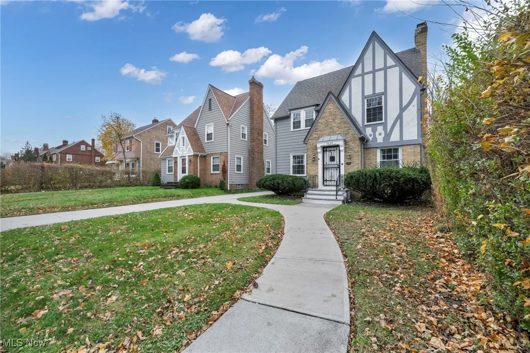 Tudor house featuring a front lawn, a chimney, brick siding, stucco siding, and a residential view