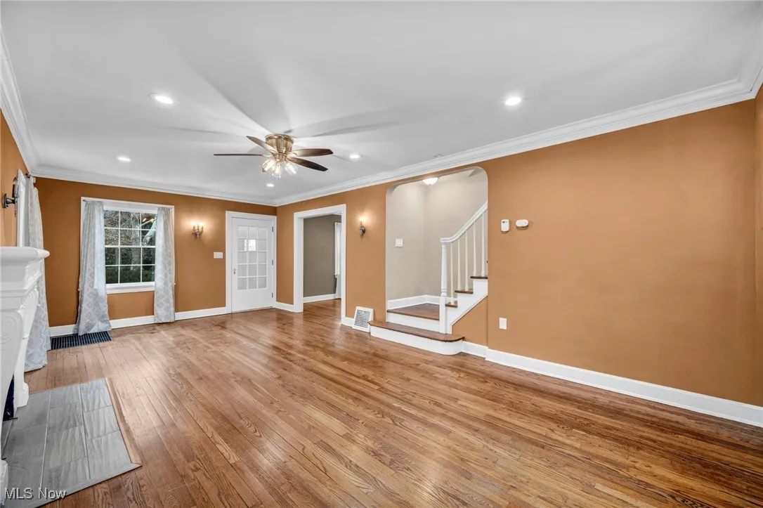 Unfurnished living room featuring crown molding, light wood-type flooring, stairway, recessed lighting, and ceiling fan