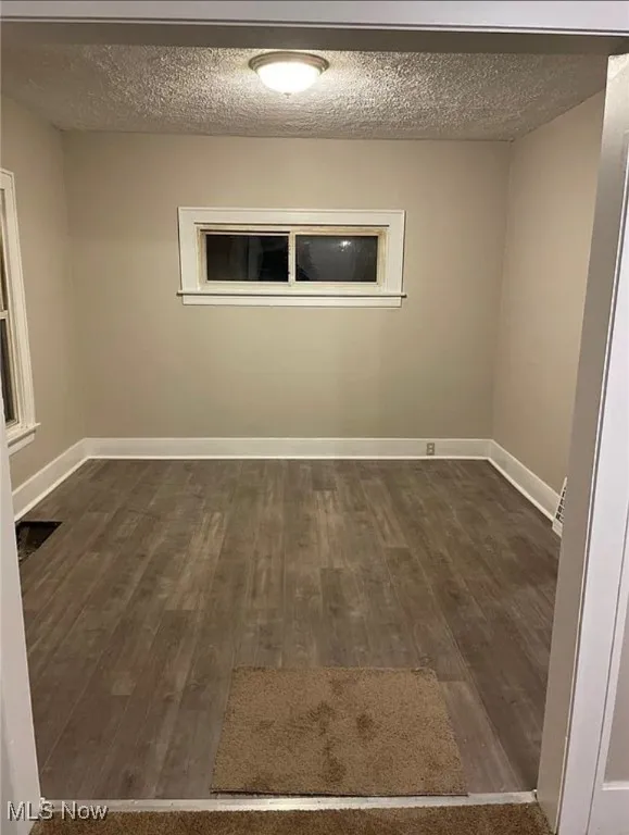 Spare room with a textured ceiling and dark wood-type flooring
