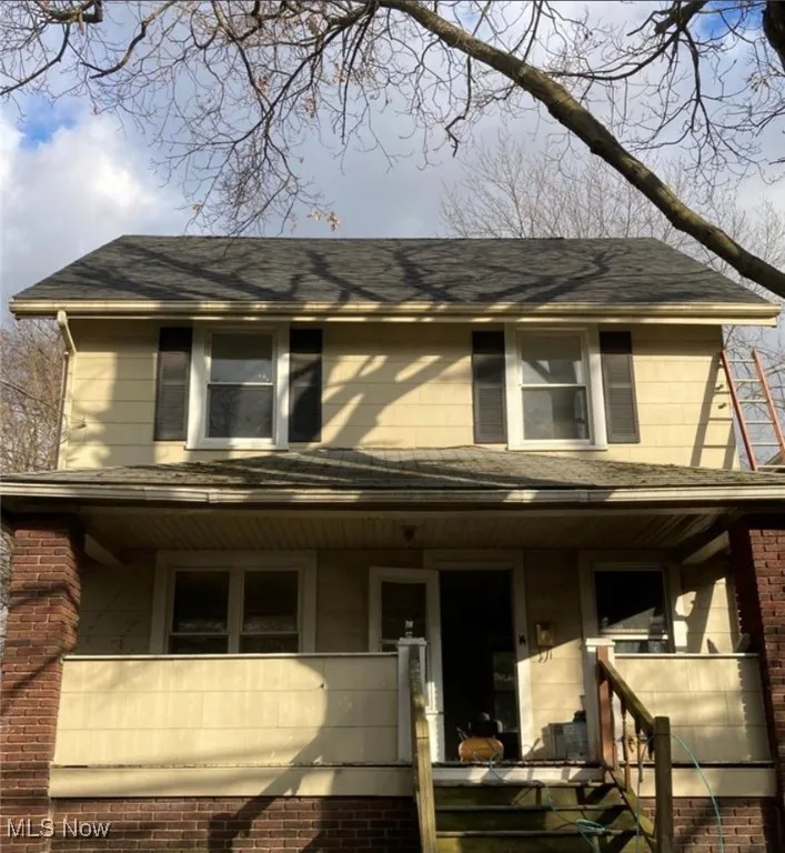 View of front of house with covered porch, a shingled roof, and stairs