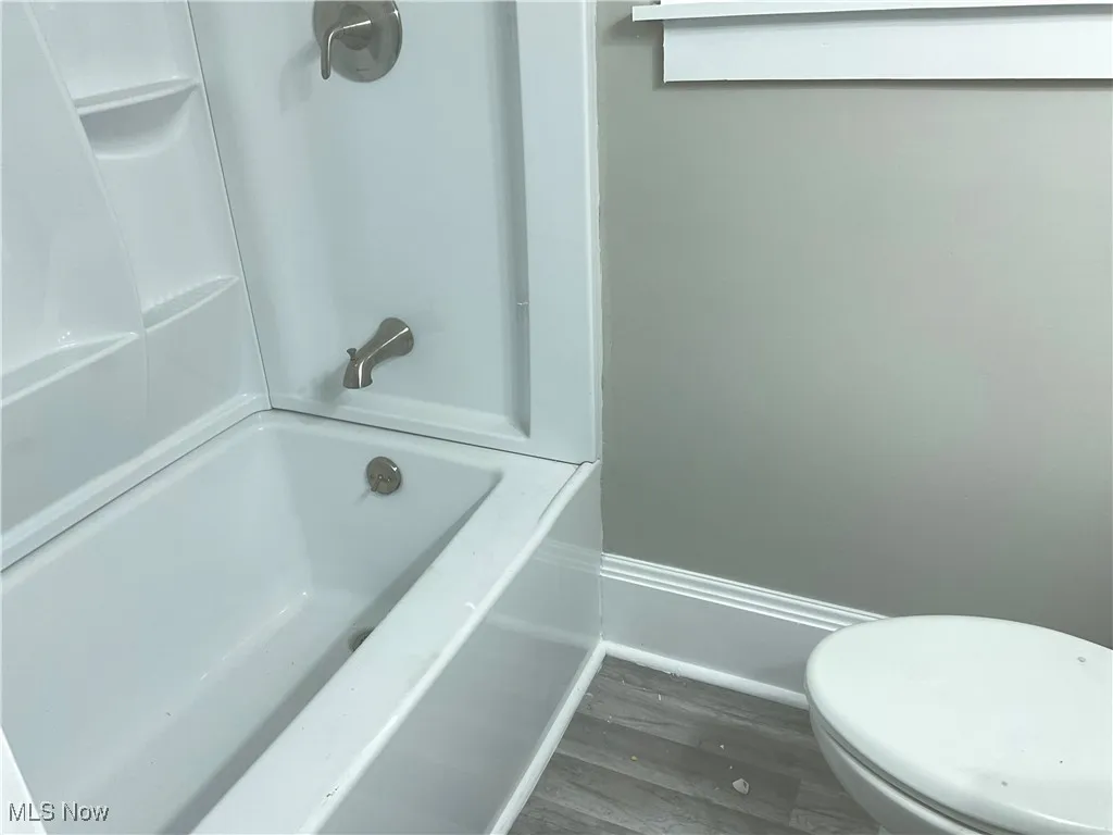 Bathroom featuring dark wood-style floors and shower / washtub combination