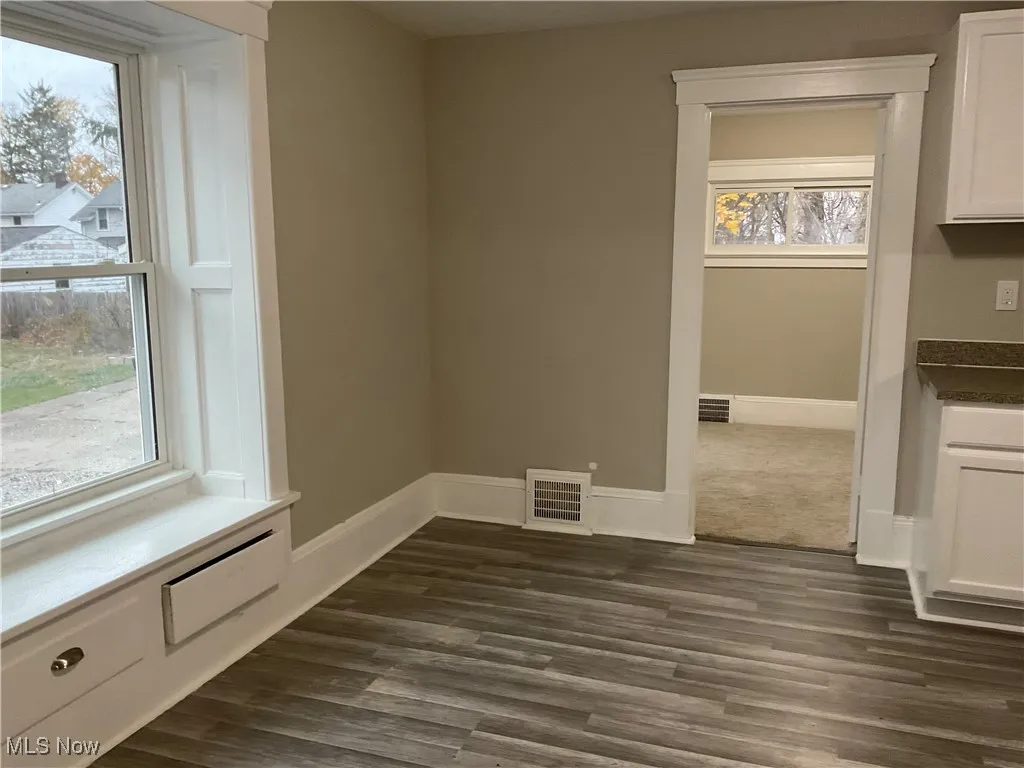 Unfurnished dining area featuring dark wood-style flooring