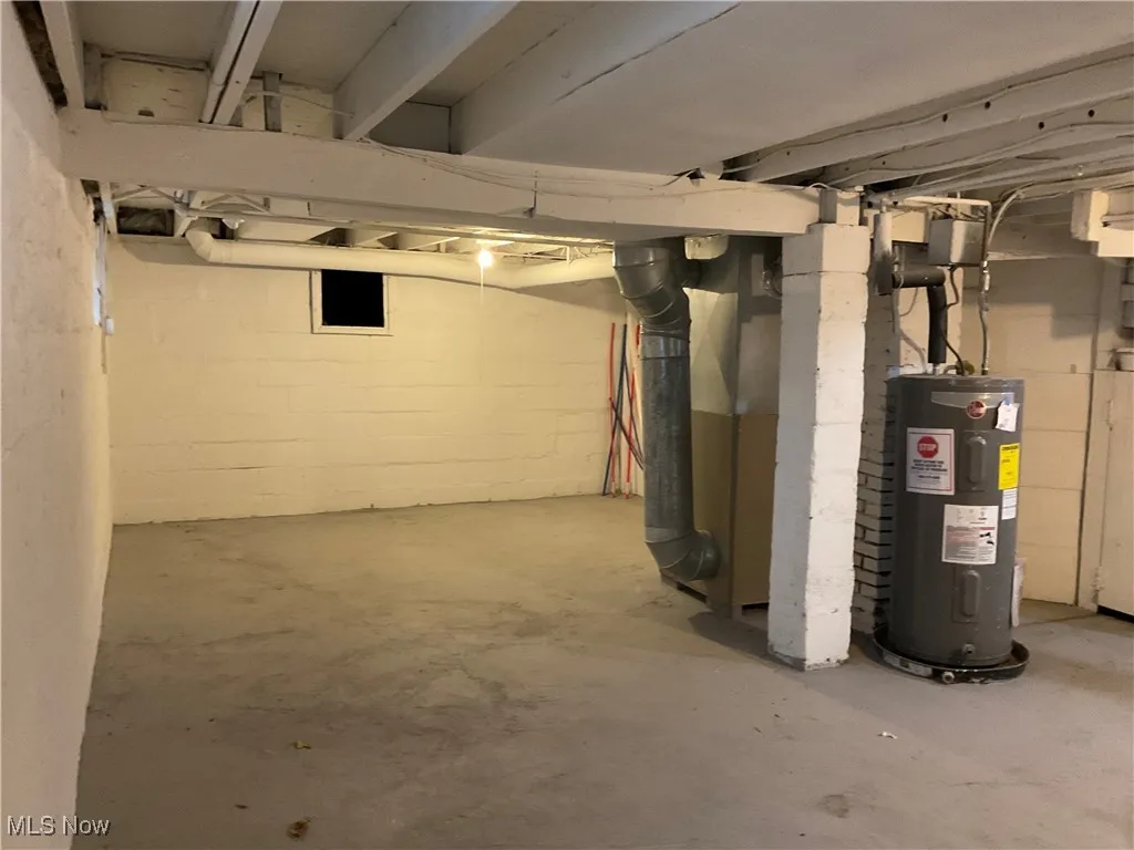 Unfinished below grade area featuring electric water heater and heating unit