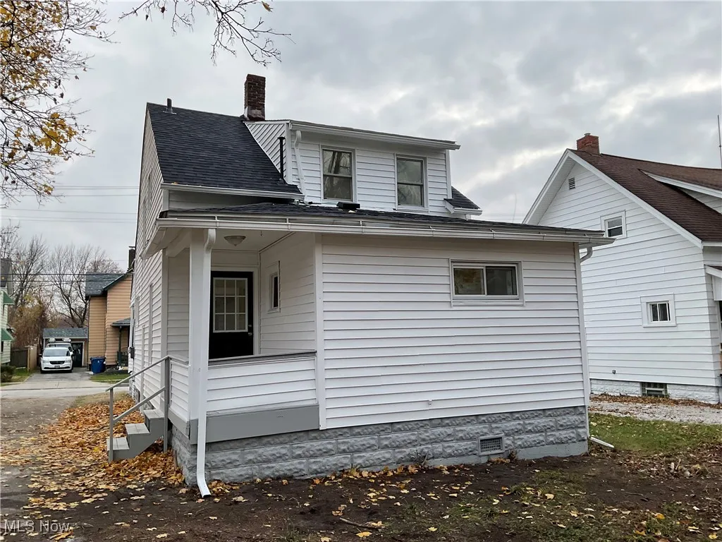 Back of property featuring a porch, roof with shingles, and a chimney