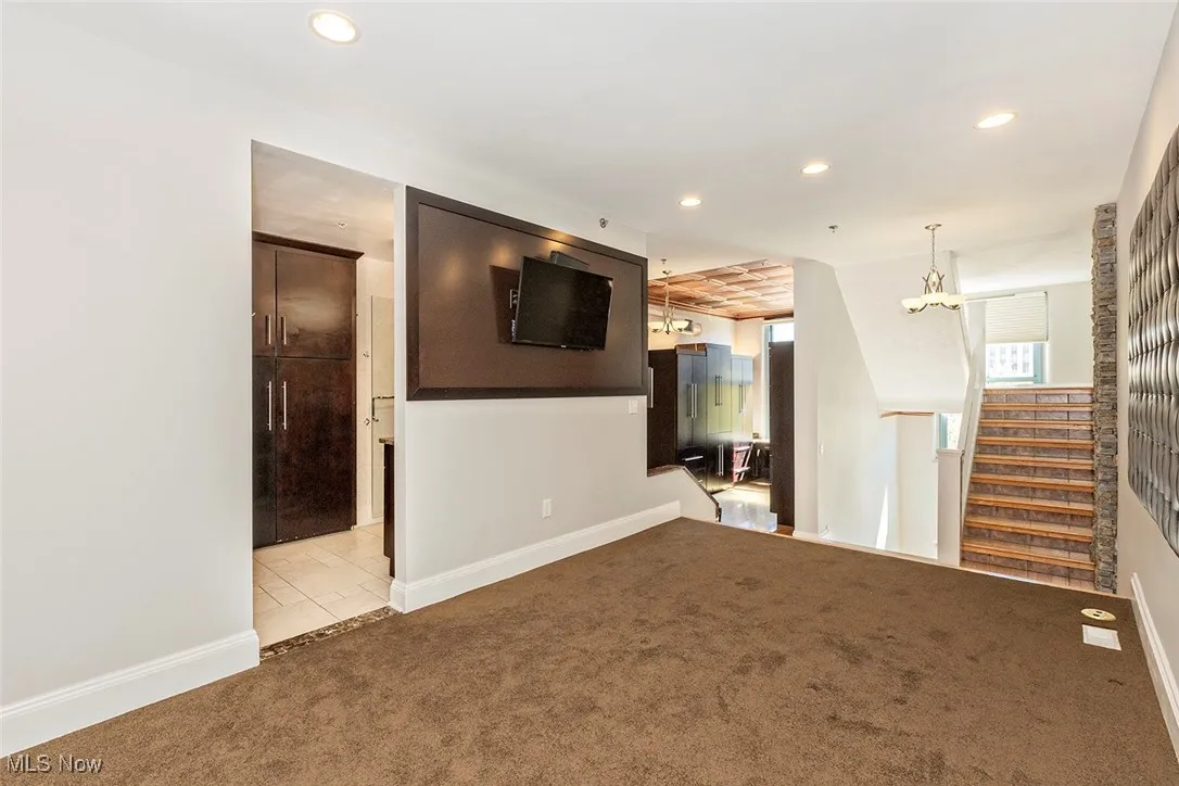 Unfurnished room with carpet flooring, a chandelier, recessed lighting, and stairs