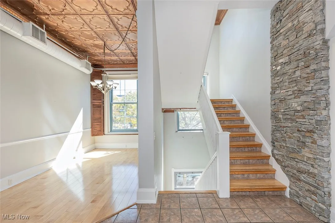 Stairs featuring a chandelier, wood finished floors, and an ornate ceiling
