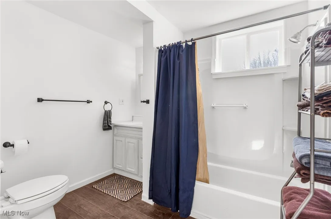 Full bath featuring vanity, wood tiled floors, and shower / bath combo with shower curtain