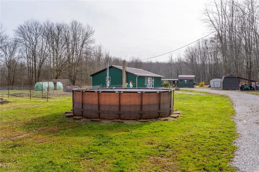 View of grassy yard featuring an outdoor pool and a shed
