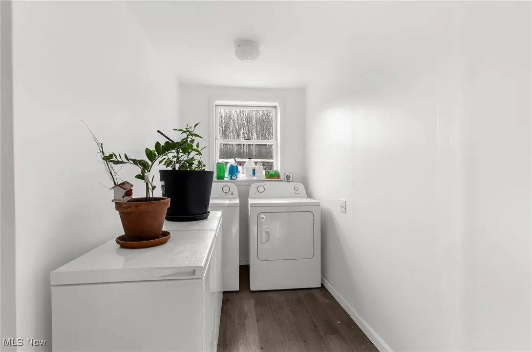 Laundry room featuring dark wood LVT flooring and washer and dryer