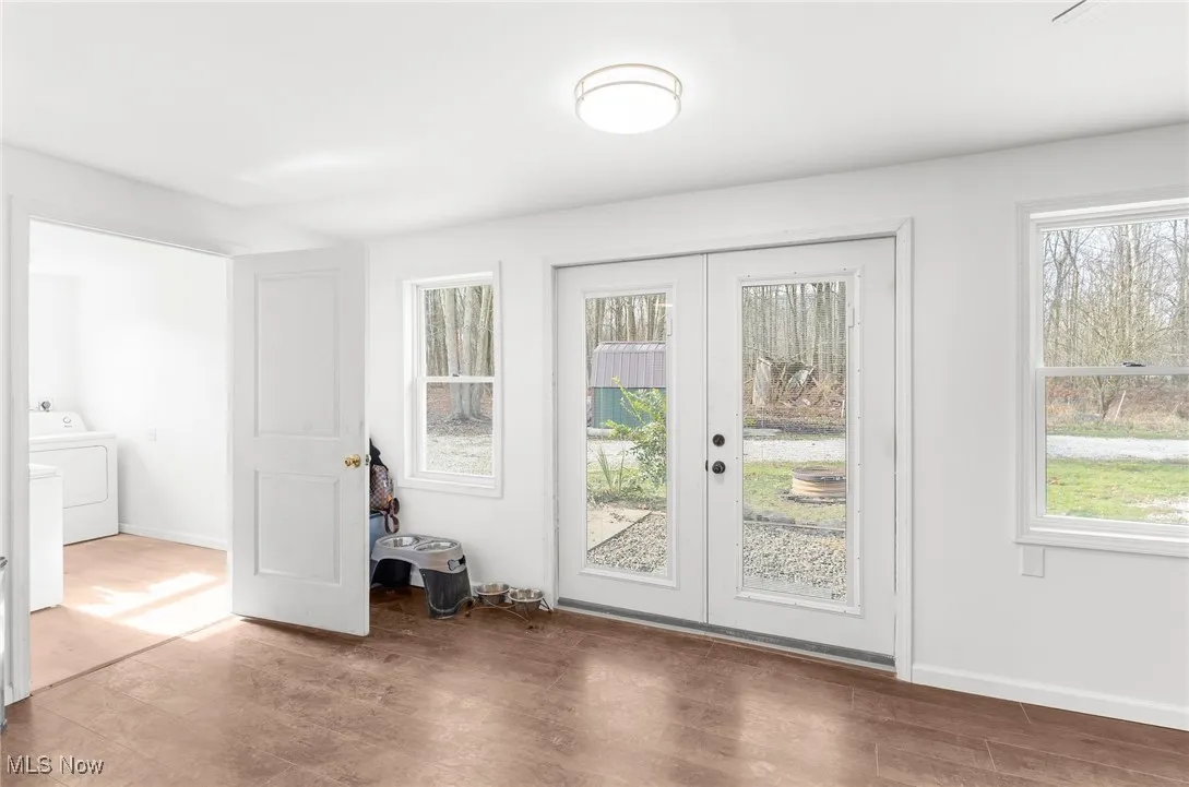 Doorway to outside featuring french doors, wood finished floors, and independent washer and dryer