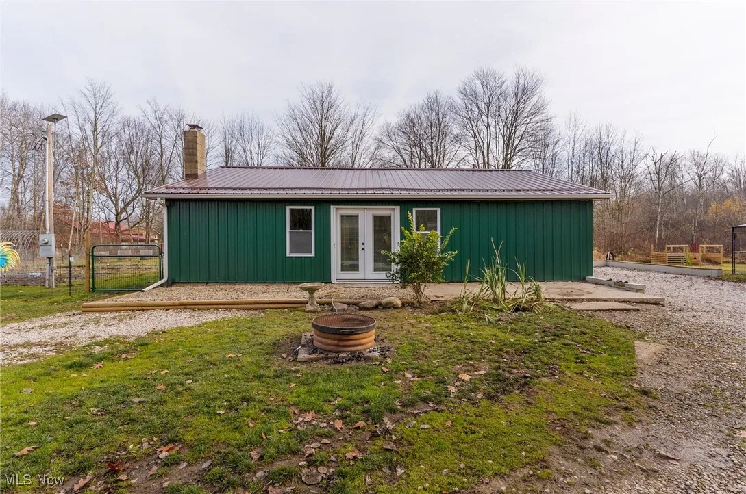 View of front of home with a fire pit, a chimney, french doors, and a metal roof