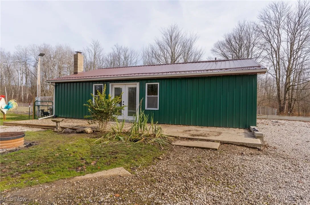 View of property exterior with a metal roof, a chimney, and french doors