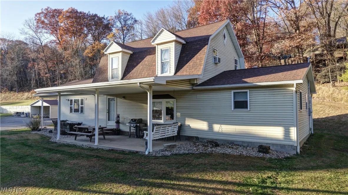 Rear view of property featuring roof with shingles, a lawn, and a gambrel roof