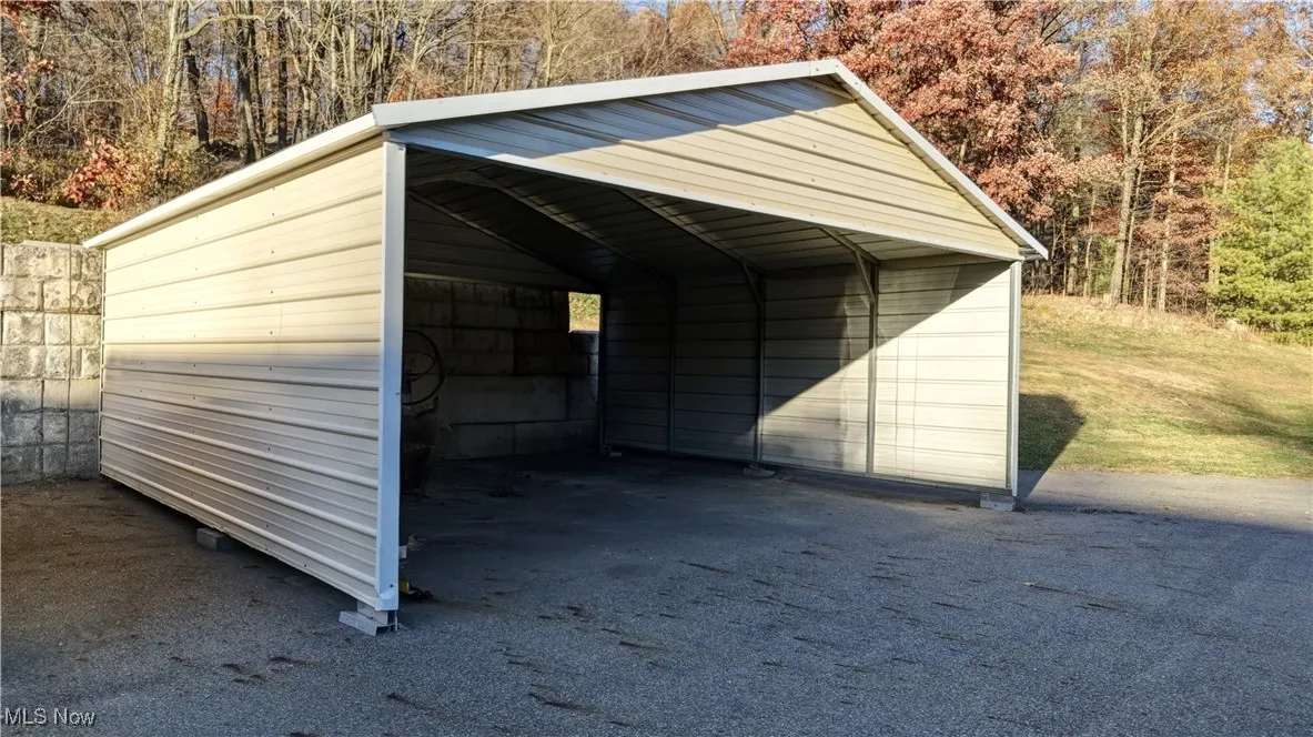 View of outdoor structure with a carport and a view of trees