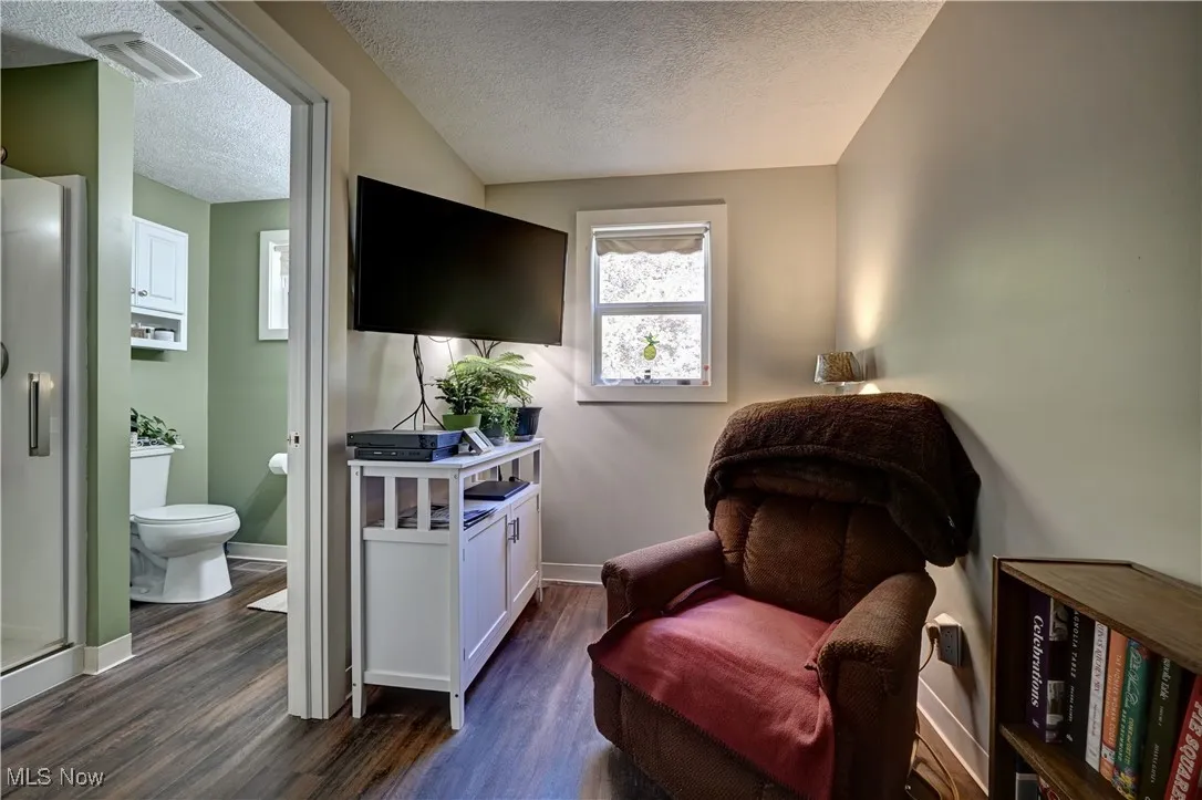 Living area featuring dark wood finished floors and a textured ceiling