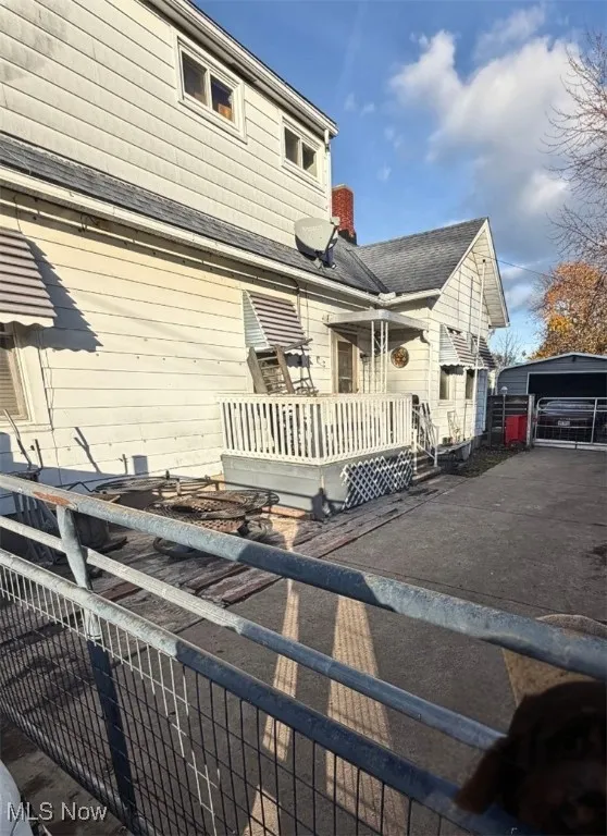 View of side of home with a deck, a detached garage, and an outbuilding