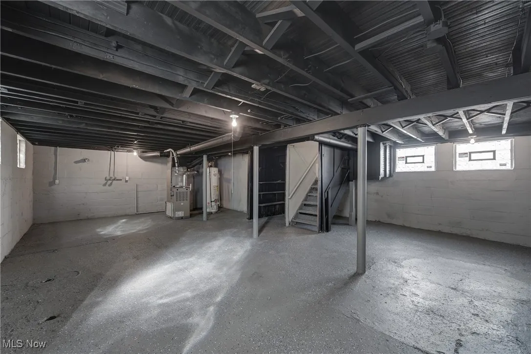 Basement with stairs, heating unit, and water heater