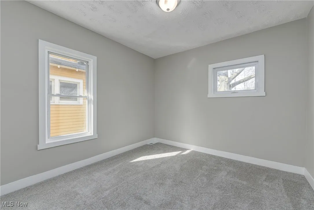 Carpeted spare room with baseboards and a textured ceiling